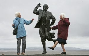 two elderly ladies copying eric morecambe statue